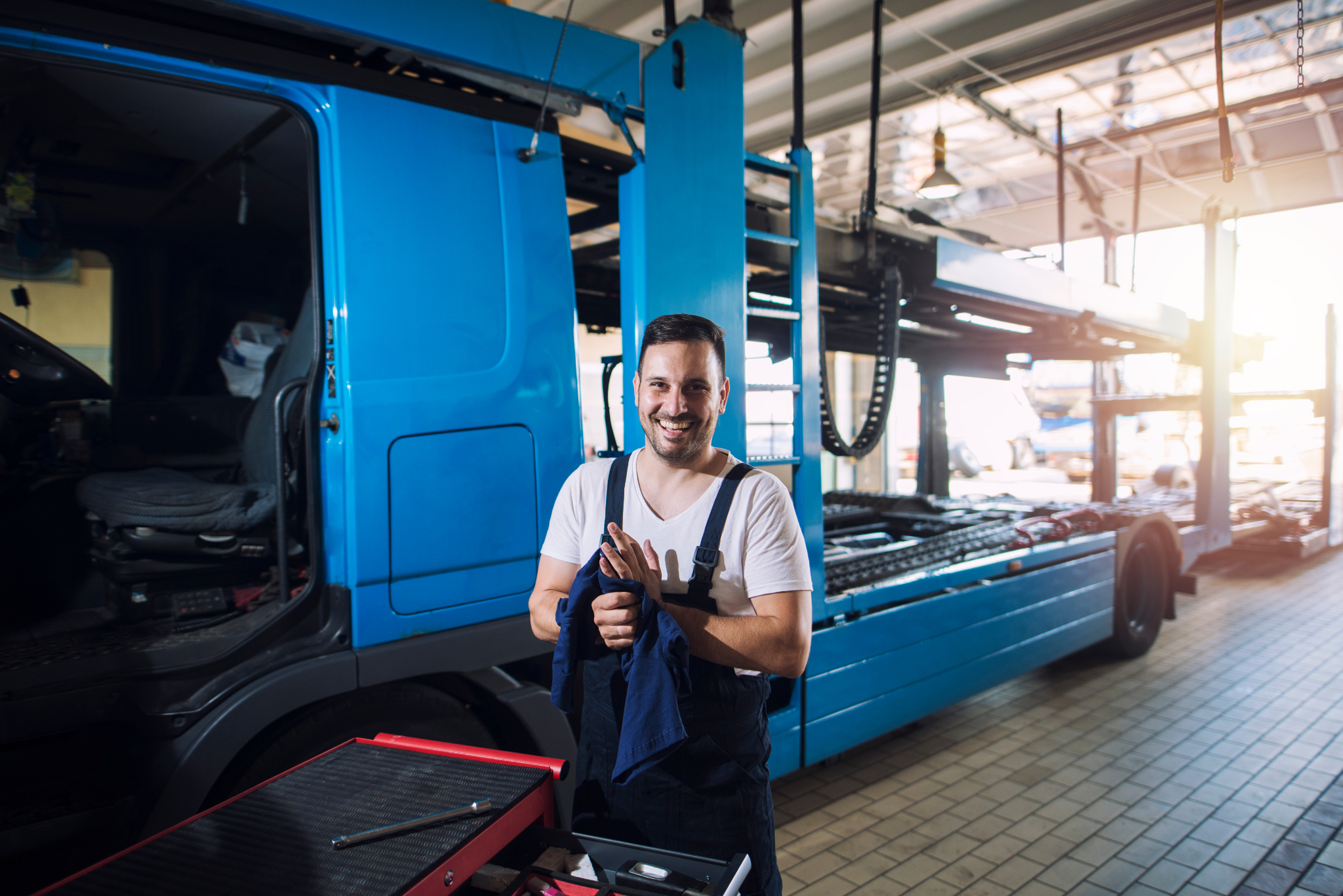 Person in Arbeitskleidung vor einem LKW in einer Werkstatt